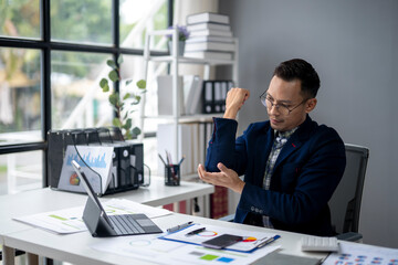 Obraz premium A man in a blue jacket is typing on a laptop computer