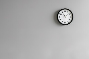 Minimalist black and white wall clock on empty grey background