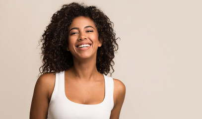 Portrait of laughing young woman standing against light background