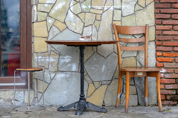 Old chair and old table near stone wall. Retro style.