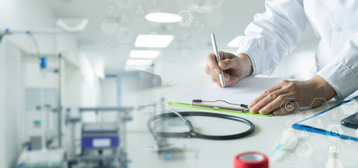 A doctor makes a note while sitting at a desk in a clinic.