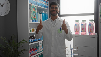 Handsome young hispanic man wearing a lab coat giving thumbs up while standing in a well-stocked pharmacy store