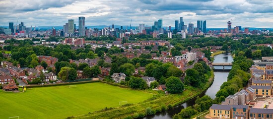 Aerial view of Manchester cityscape with river Irwell, park, and buildings.