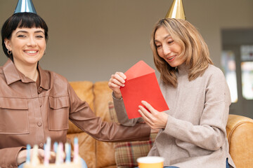 Two Women Celebrating  Birthday While Wearing Party Hats In  Cozy Living Room