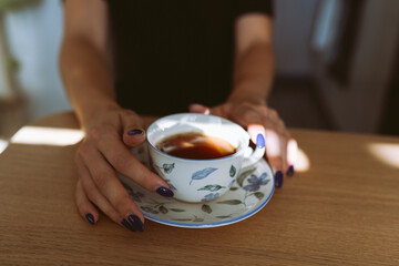 hands young woman holding cup on saucer with green tea