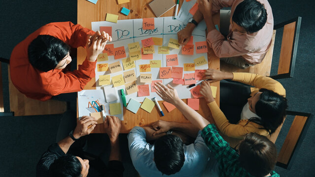 Top view of people writing and making scrum task board while writing marketing and planning strategy at colorful sticky notes. Smart team manage work performance by using kanaban board. Convocation.