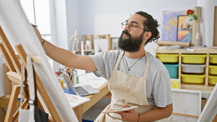 Bearded man painting in a bright art studio, showcasing creativity and concentration.