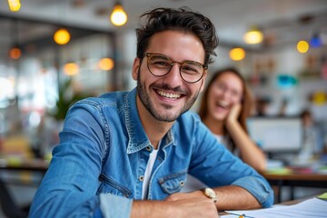 Fototapeta premium Happy businessman with glasses smiling and looking at the camera while working on financial documents in the office. Beautiful woman with glasses laughing and looking at her computer screen