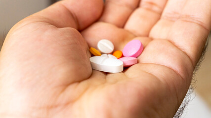 male model holding various health pills in his hand