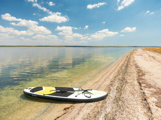 view to sup board on the lonely beach in summer day under sky with clouds with nobody