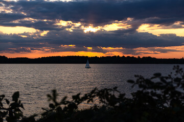 Sailing boat at sunset on Lake Cospuden in Markkleeberg. Beautiful atmosphere with orange sky....