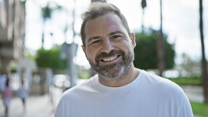 Fototapeta premium A handsome middle-aged hispanic man with grey hair smiling outdoors in a city setting.
