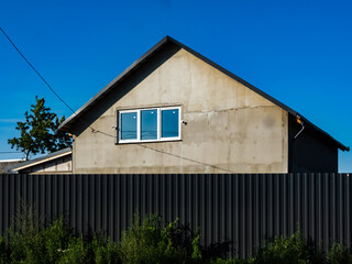 fence made of metal corrugated sheets near a house under construction