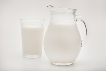 Melted milk in a milk jug and in a glass on a white background. Milk in a bowl.