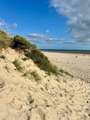 Beach sand dunes with green grass and sky with clouds