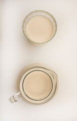 Melted milk in a milk jug and in a glass on a white background. Milk in a bowl.