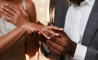 Close up of african man in love putting wedding ring on his woman finger