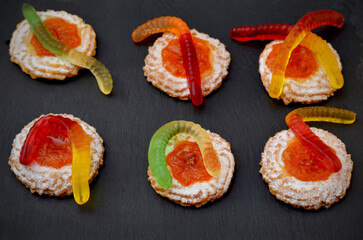 funny snack cookies with gummy worms on a dark background