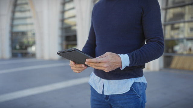 Mature man in casual wear holding tablet on urban street, combining technology with outdoor ambience.