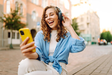 Young woman using headphone for listening nice music and walking in city. Female love listen music that make her relax and enjoying life. Travel, tourism, technology, blogging concept.