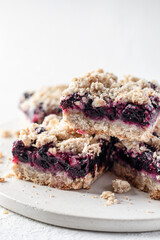 Baked oatmeal bars or crumble squares with fresh blueberry on white background, close up. Menu, recipe