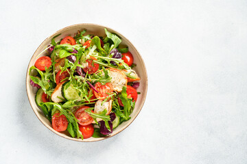 Dash diet recipe. Green salad with baked chicken breast, fresh salad leaves and vegetables. Top view on white background.