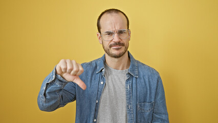 A bearded, bald man wearing glasses and a denim shirt expressing disapproval with a thumbs-down...