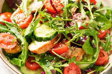 Green salad with baked chicken breast, fresh salad leaves and vegetables. Close up.