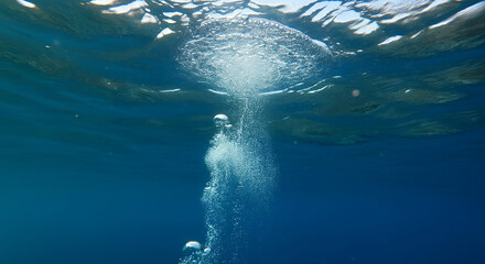 Fototapeta premium Underwater view with bubbles rising to the surface in a deep blue ocean. the serenity and mystery of the underwater world created with generative ai.