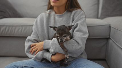 A young woman holding a chihuahua in a cozy living room, expressing care and companionship.