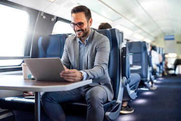 Handsome middle age businessman using his laptop computer while traveling with high-speed train....
