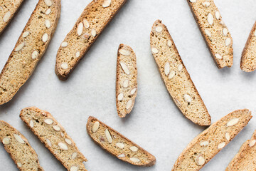almond biscotti on white parchment lined tray, almond cantucci cookies on a white board, flatlay of slices of biscotti cookies or twice baked cookies