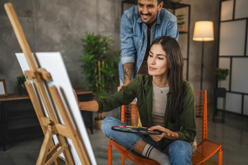girlfriend learn from her boyfriend how to do paint and hold brush
