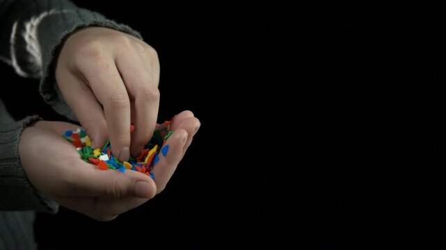 Child damage from microplastic. A teen hand hold microplastic against black. A concept of plastic dust on Earth.