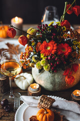 Beautiful seasonal decorated Thanksgiving table for cozy family dinner or fall luxury countryside wedding. Elegant beautiful setting for holiday event, party, reception. Wineglasses and fancy dishes.