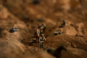 Miniature military figures in the sand in a mountainous area, a game of war with soldiers.