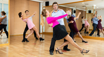 woman choreographer paired with experienced dancer on floor of training hall dancing waltz
