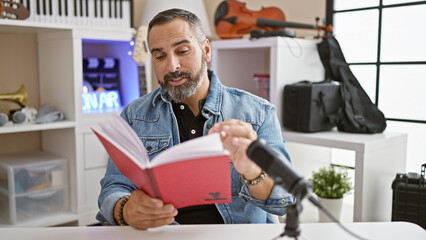 A mature hispanic man with grey beard reads in a music studio