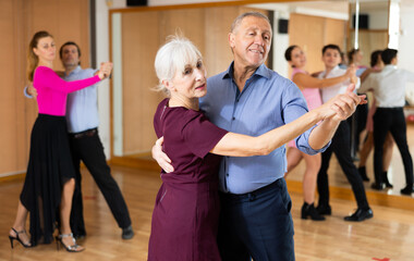 among small group of students at dance lesson, older positive partners dance waltz