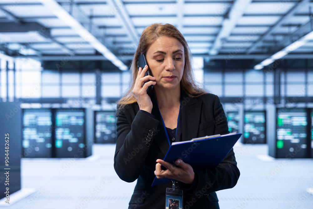 Poster manager maintaining accurate documentation of data center equipment, chatting on mobile phone with e