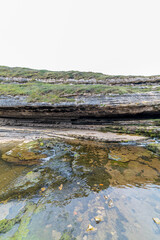 Picturesque waterfall flowing over layered rock formations with lush green moss in Cantabria, Spain. Ideal for nature, travel, and landscape themes.