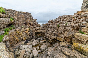 Captivating view of historic stone ruins perched on a rugged cliff in Cantabria, Spain, with the ocean in the background. Ideal for travel, history, and landscape themes.