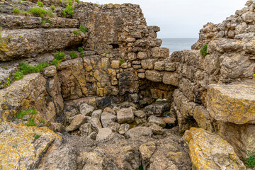 Captivating view of historic stone ruins perched on a rugged cliff in Cantabria, Spain, with the ocean in the background. Ideal for travel, history, and landscape themes.