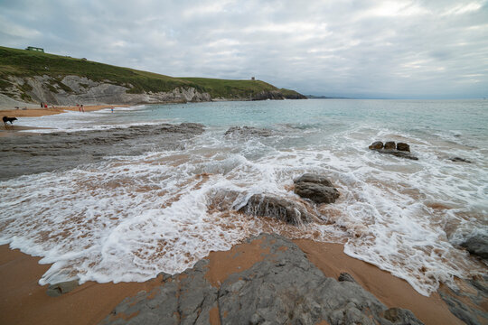 Tranquil scene of Tagle Beach in Cantabria, Spain, showcasing rugged rocks, gentle waves, and an expansive horizon. Perfect for travel, nature, and coastal themes.