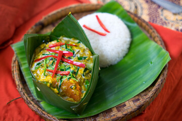 Authentic Cambodian Amok – Traditional Fish Curry Steamed in Banana Leaves with Rice, Garnished...