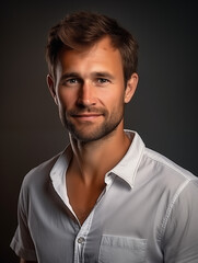 Obraz premium Studio portrait of a handsome young man with stubble wearing a casual white shirt on a dark background