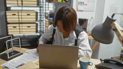African american woman working focused in a cluttered police office surrounded by files and a...