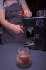 Woman Barista operates a machine to prepare delicious coffee, using the coffee machine
