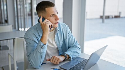 Handsome hispanic man talking on smartphone at university library with laptop