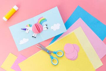 Paper cutout of a unicorn flying in the sky, presented as a whole pastel-colored card from an overhead perspective. Ideal for creative crafts and magical-themed designs